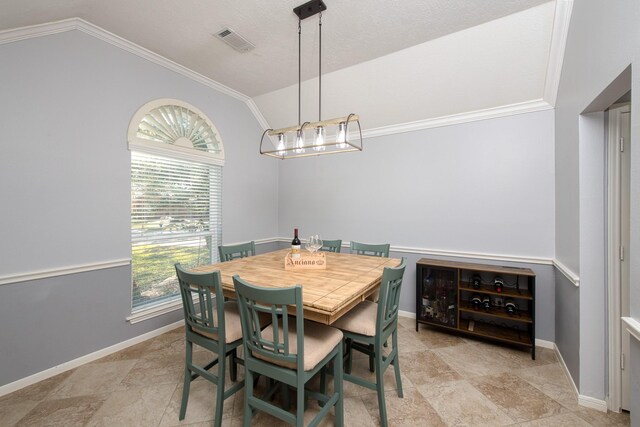 dining room with baseboards, visible vents, vaulted ceiling, and crown molding