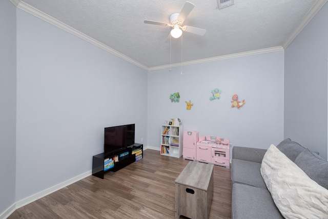 living room with a textured ceiling, ornamental molding, wood finished floors, and baseboards