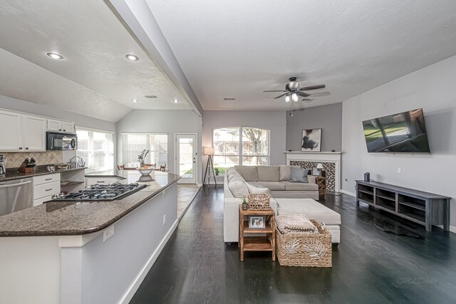 living room featuring a fireplace, baseboards, dark wood-style flooring, and a wealth of natural light