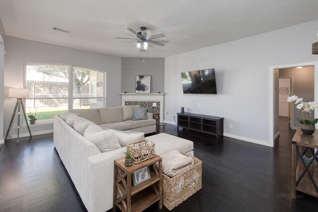 living area with dark wood-style floors, ceiling fan, visible vents, and baseboards