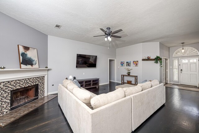 living area featuring a textured ceiling, a tiled fireplace, visible vents, and wood finished floors