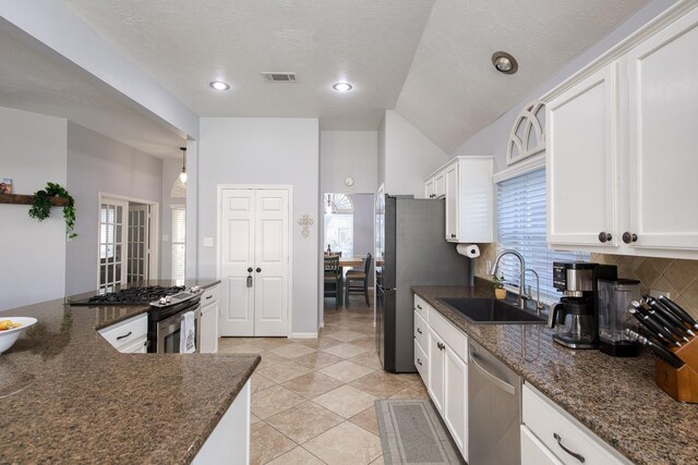 kitchen with visible vents, white cabinets, decorative backsplash, stainless steel appliances, and a sink