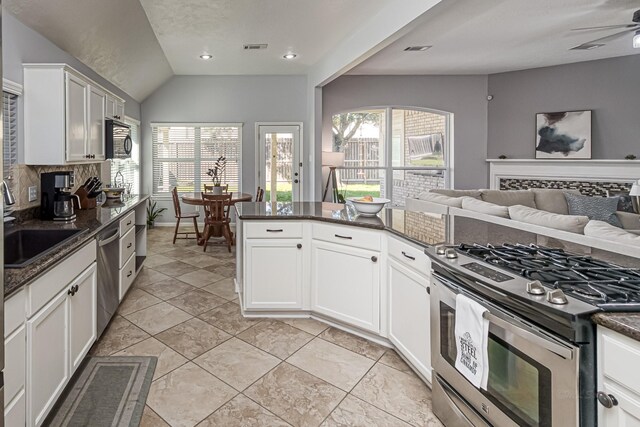 kitchen with stainless steel appliances, visible vents, open floor plan, dark stone counters, and tasteful backsplash