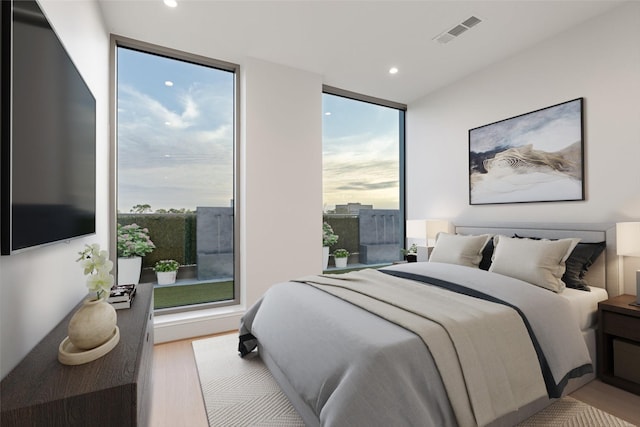 bedroom featuring floor to ceiling windows, light wood-style flooring, recessed lighting, and visible vents