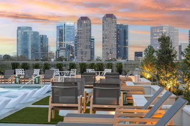 patio terrace at dusk with outdoor dining space and a view of city