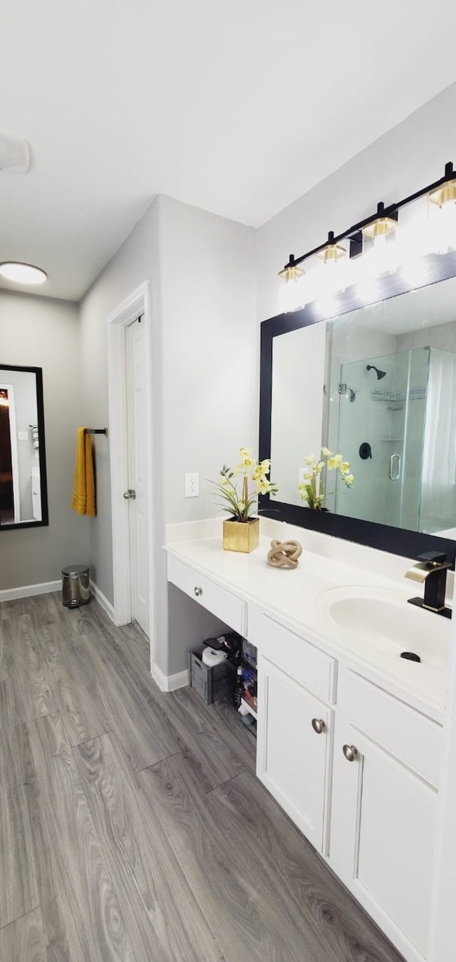 full bath with wood finished floors, a shower stall, vanity, and baseboards