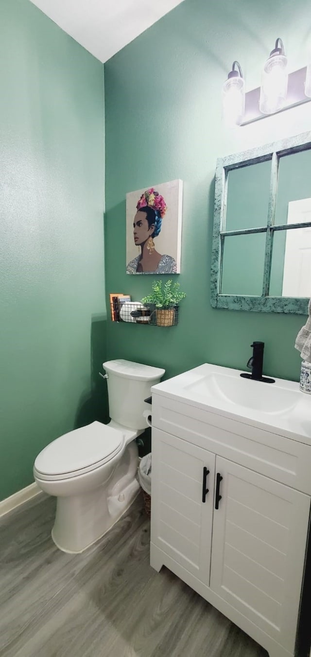 bathroom with baseboards, vanity, toilet, and wood finished floors