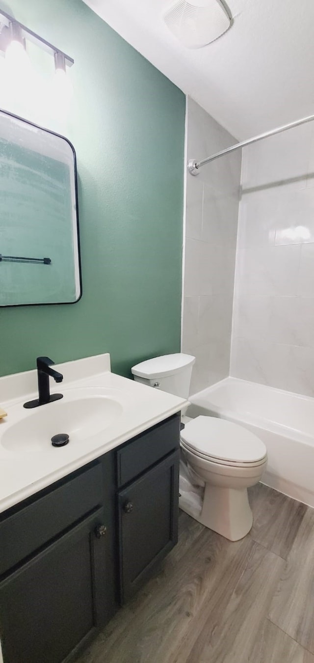 bathroom featuring toilet, bathing tub / shower combination, wood finished floors, and vanity