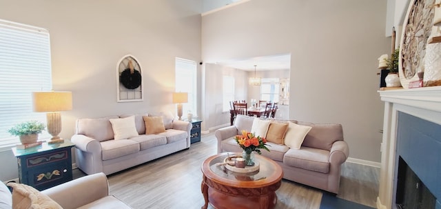 living area featuring baseboards, a fireplace, a high ceiling, and wood finished floors