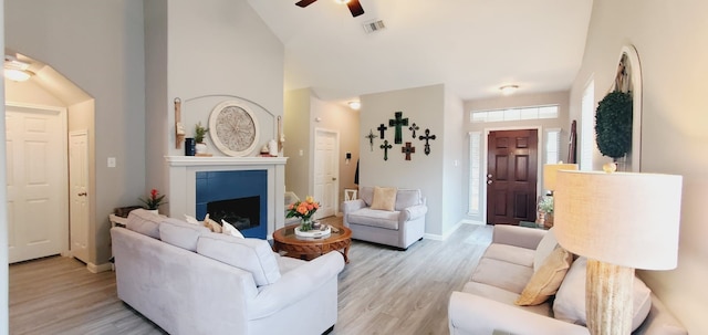 living area featuring a ceiling fan, a fireplace, light wood-style floors, and visible vents