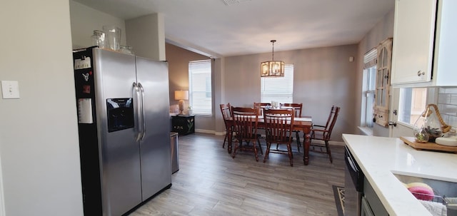 dining space with light wood-type flooring, baseboards, visible vents, and a notable chandelier