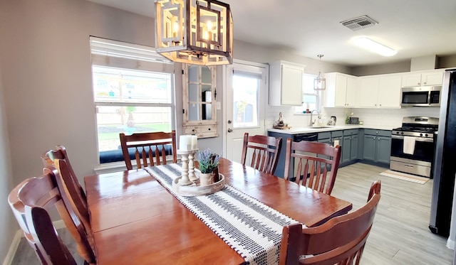 dining area featuring light wood-style flooring and visible vents