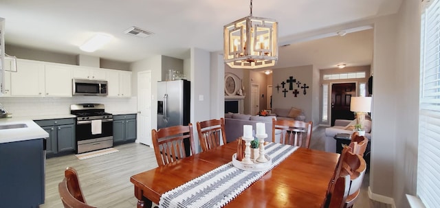 dining area with visible vents, a notable chandelier, and light wood-style flooring