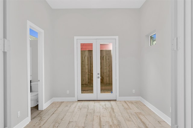 spare room featuring plenty of natural light, baseboards, wood finished floors, and french doors