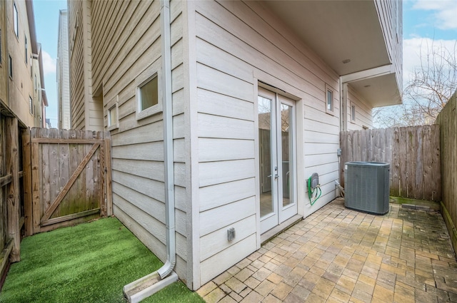 exterior space featuring a patio, a fenced backyard, a gate, cooling unit, and french doors