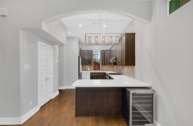 kitchen with stainless steel range with gas cooktop, light countertops, backsplash, dark brown cabinets, and beverage cooler