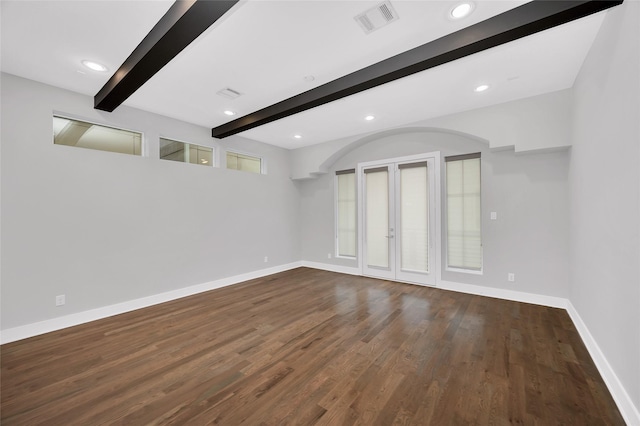 empty room with beamed ceiling, wood finished floors, visible vents, and baseboards