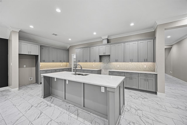 kitchen featuring marble finish floor, gray cabinets, a kitchen island with sink, a sink, and baseboards