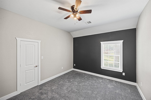 empty room featuring baseboards, visible vents, a ceiling fan, lofted ceiling, and dark carpet