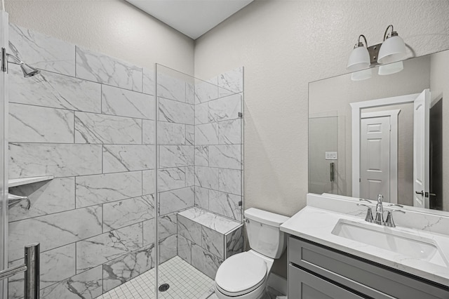 bathroom featuring a textured wall, a stall shower, vanity, and toilet