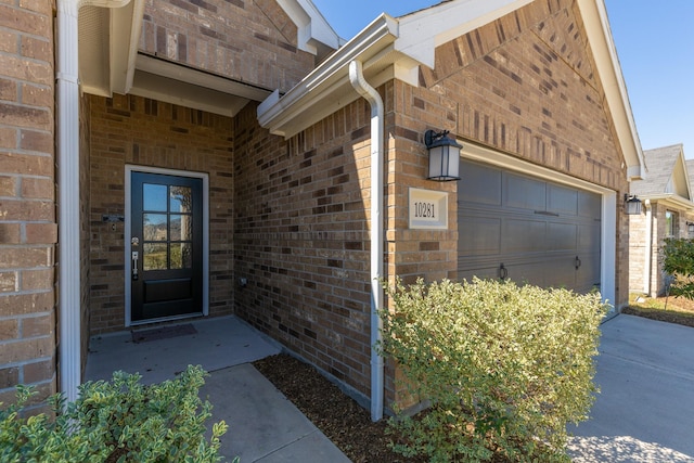 doorway to property featuring brick siding and an attached garage