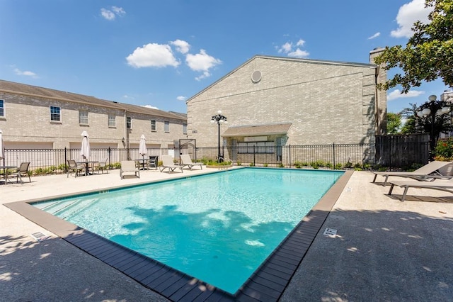 community pool with a patio area and fence