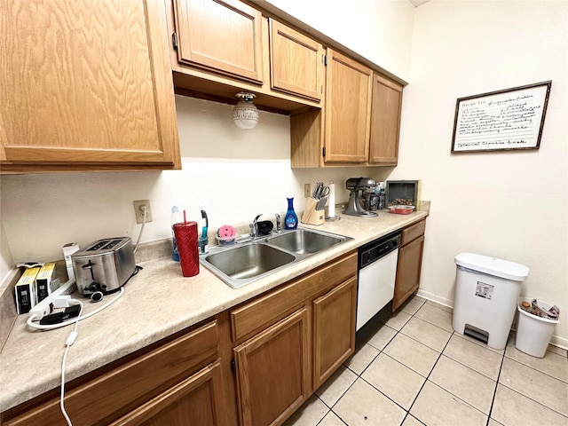 kitchen featuring light tile patterned floors, baseboards, dishwasher, light countertops, and a sink