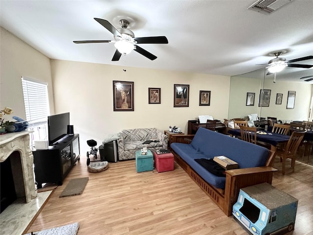 living room with light wood-style floors, visible vents, and a ceiling fan