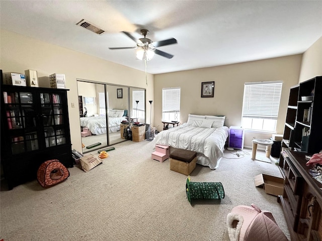 carpeted bedroom featuring a closet, visible vents, and a ceiling fan