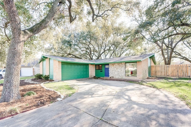 view of front of home featuring a garage, driveway, brick siding, and fence