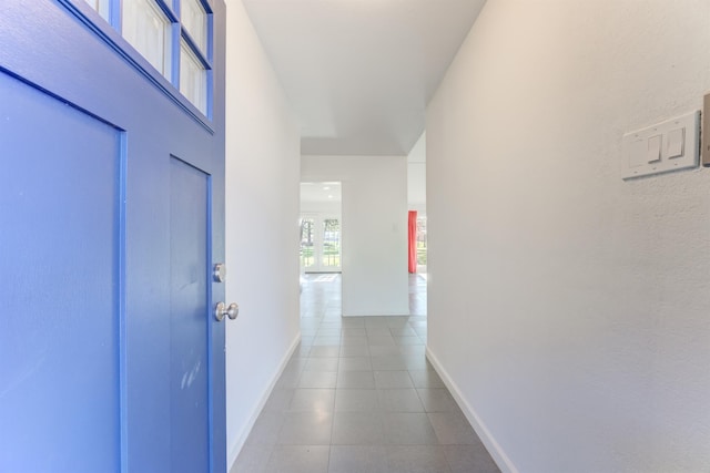 hallway with baseboards and tile patterned floors