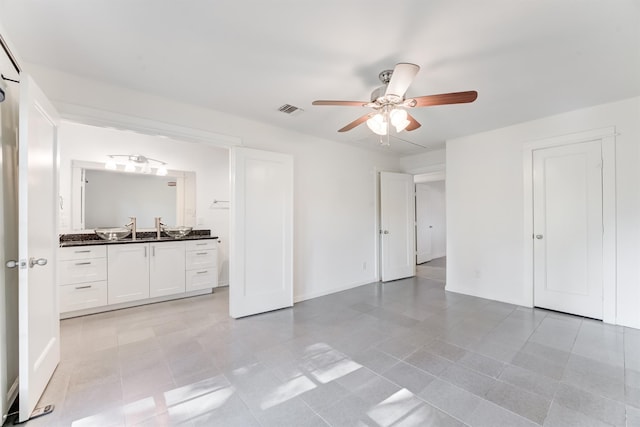 unfurnished bedroom with ensuite bathroom, visible vents, and a ceiling fan