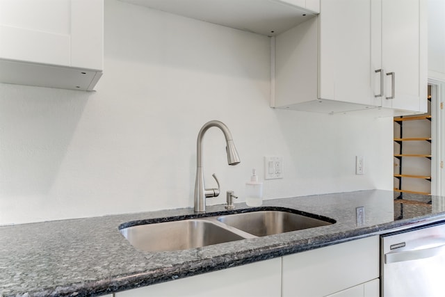 kitchen featuring dishwasher, white cabinetry, dark stone counters, and a sink