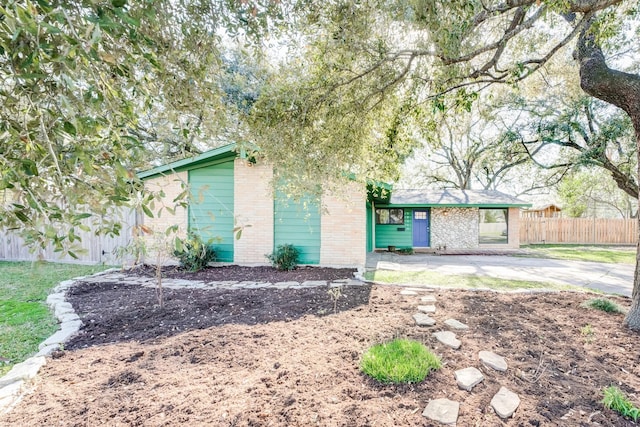 view of front of house with brick siding, a patio, and fence