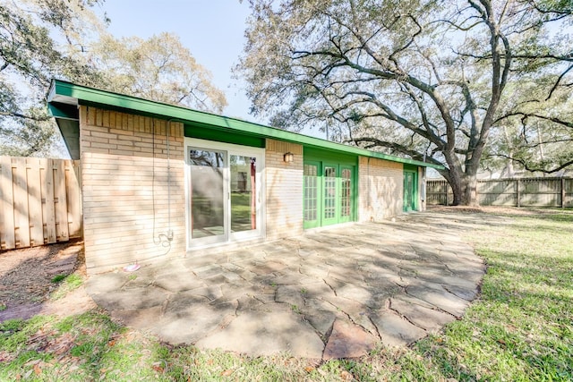 rear view of property featuring a fenced backyard, french doors, and brick siding