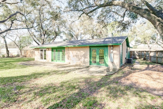 back of house with french doors, brick siding, a yard, and a fenced backyard