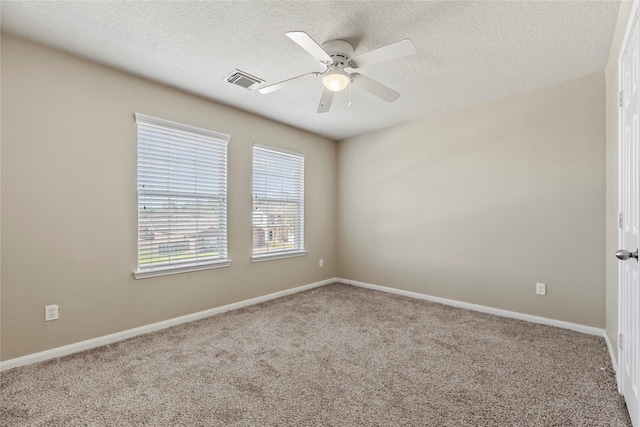 spare room with carpet, a textured ceiling, visible vents, and a ceiling fan