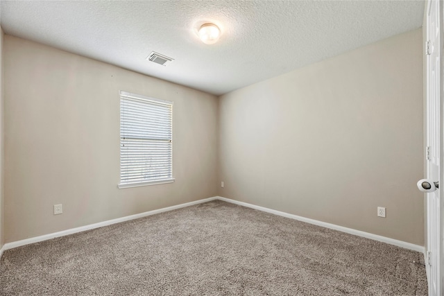 spare room featuring a textured ceiling, carpet flooring, visible vents, and baseboards