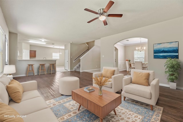 living room featuring arched walkways, wood finished floors, stairs, and baseboards