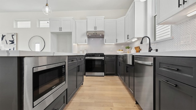 kitchen with under cabinet range hood, light wood-style floors, appliances with stainless steel finishes, and white cabinetry