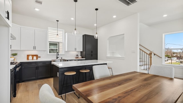 kitchen featuring tasteful backsplash, visible vents, a center island, and a sink