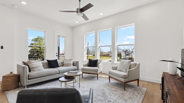 living area with recessed lighting, light wood-type flooring, a wealth of natural light, and baseboards