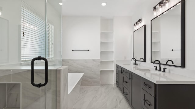 bathroom featuring a freestanding bath, double vanity, marble finish floor, and a sink