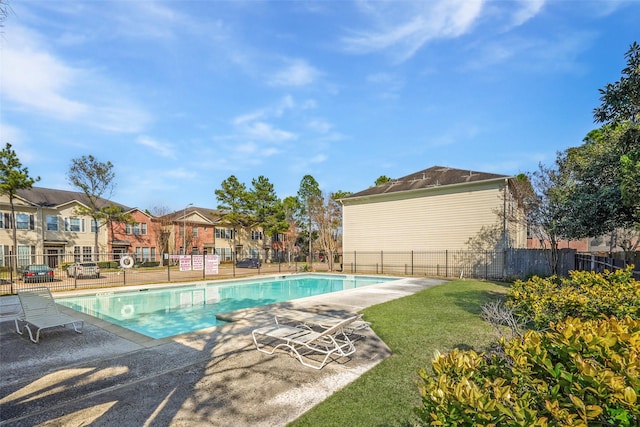 community pool with a yard, a patio area, fence, and a residential view