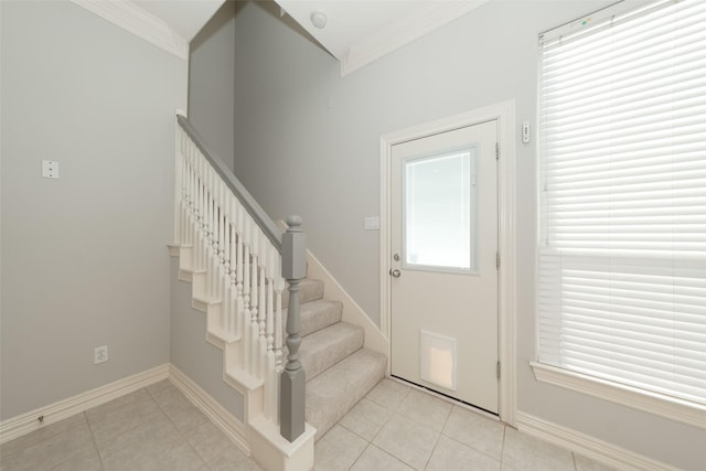 interior space with light tile patterned flooring, crown molding, baseboards, and stairs