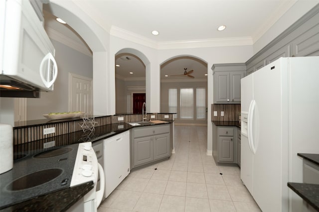 kitchen featuring white appliances, light tile patterned floors, a sink, gray cabinets, and backsplash