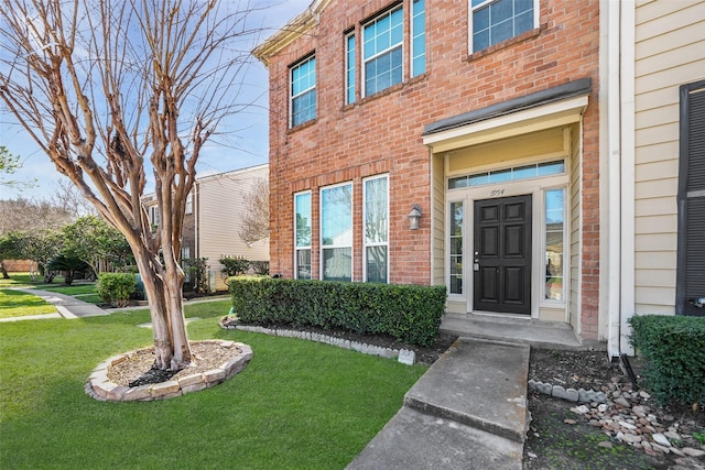 doorway to property with brick siding and a yard