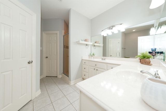 bathroom with a stall shower, double vanity, a sink, and tile patterned floors