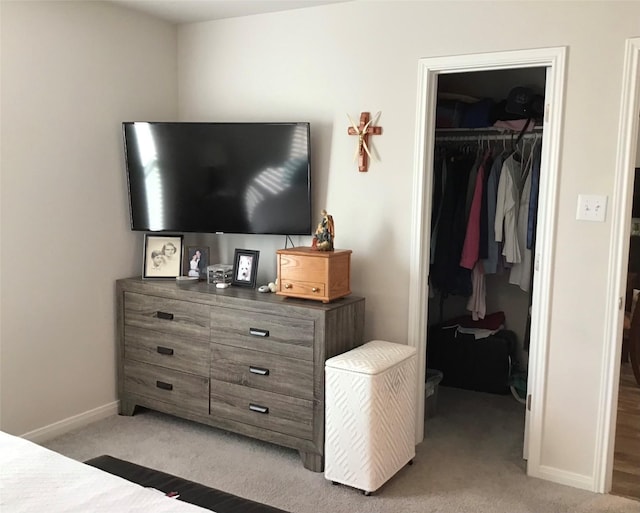 bedroom featuring baseboards, a walk in closet, a closet, and light colored carpet