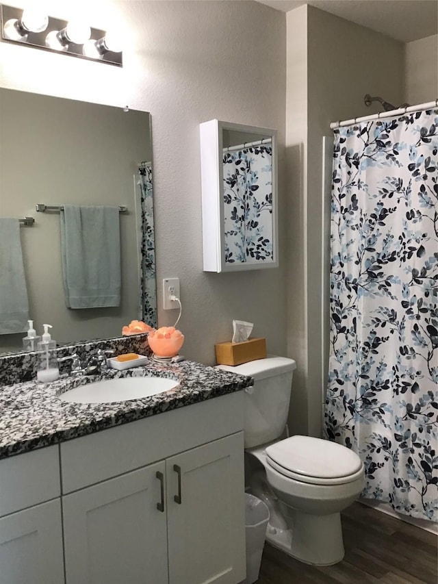 bathroom with toilet, a shower with shower curtain, wood finished floors, and vanity